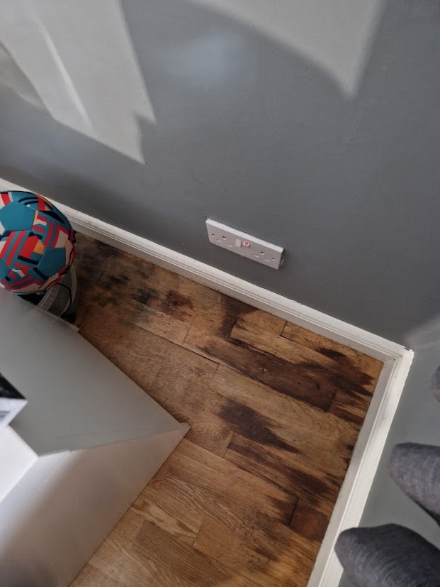 Dark water staining on a timber floor from water leak home insurance claims.