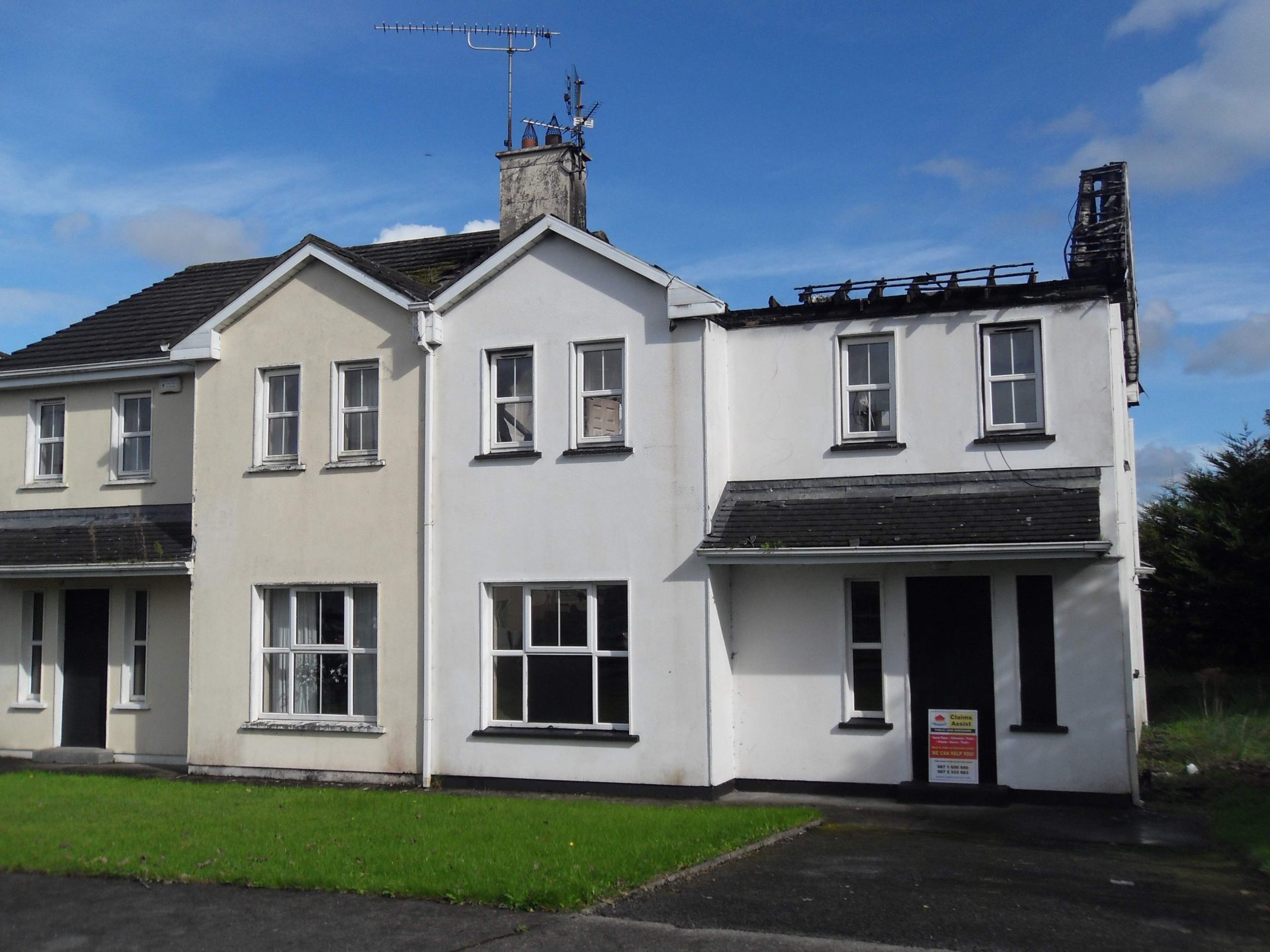 Claims Assist signage outside a fire-damaged house in Mayo where loss assessors are managing an insurance claim.