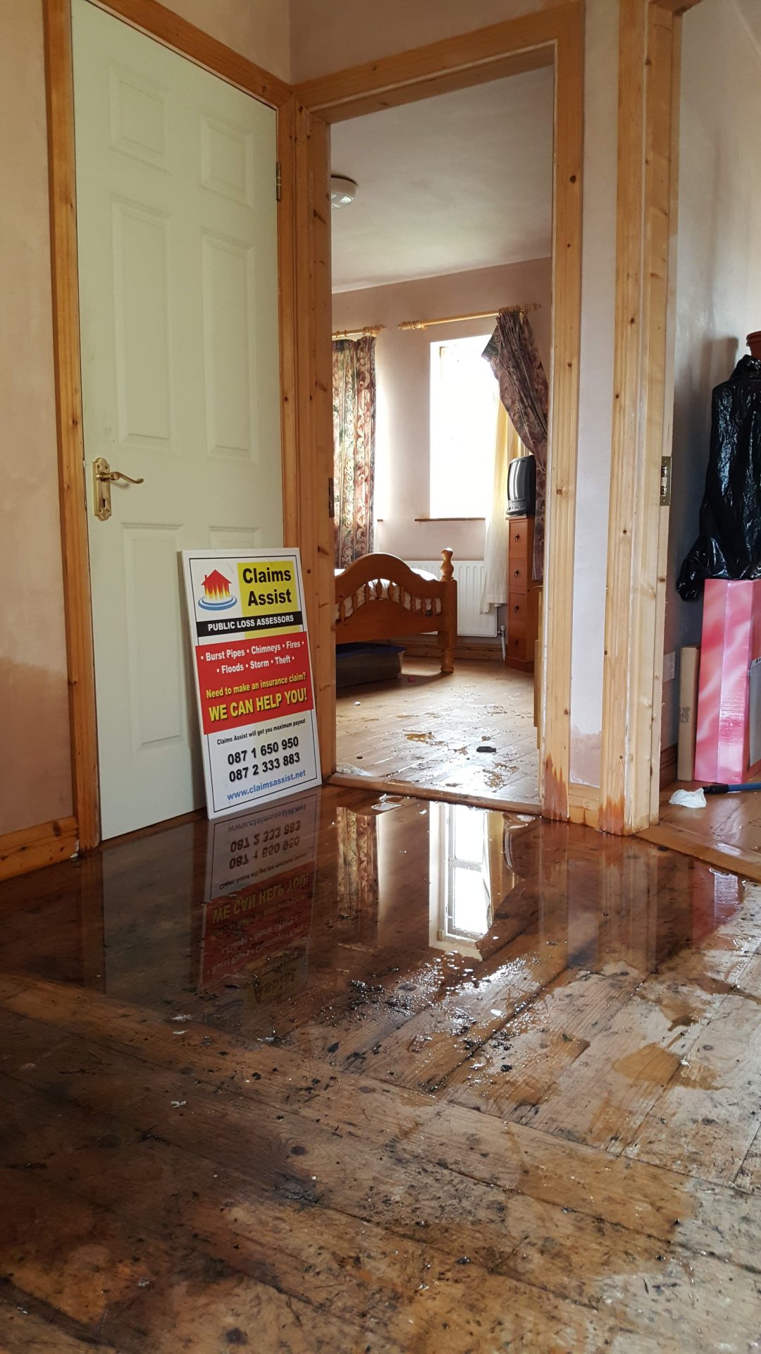 Severe internal flood water covering wooden floors in a residential hallway and bedroom in Tipperary, being managed by Claims Assist Loss Assessors.