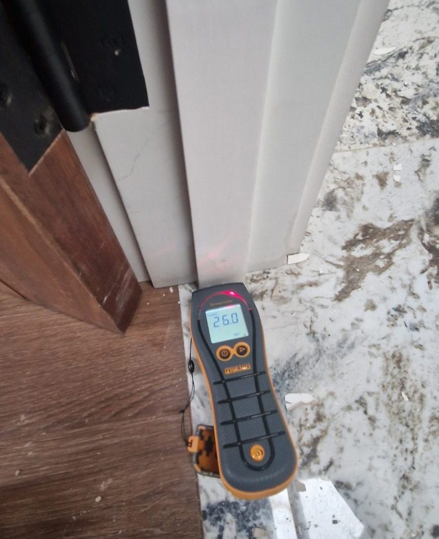 Professional moisture meter checking for damp in timber floors and door frames after a water leak in Castlebar, Mayo
