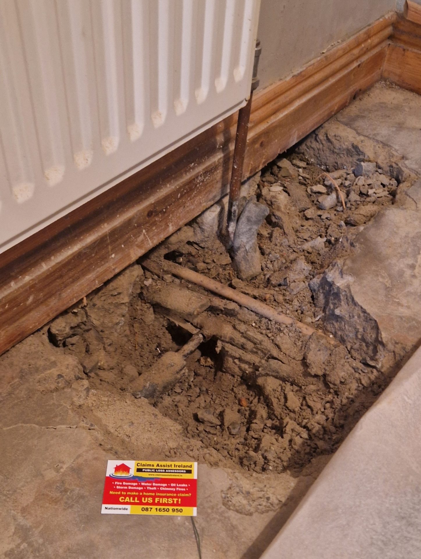 Exposed radiator pipe leak in a Shannon home with Claims Assist business card visible during an on-site insurance inspection.