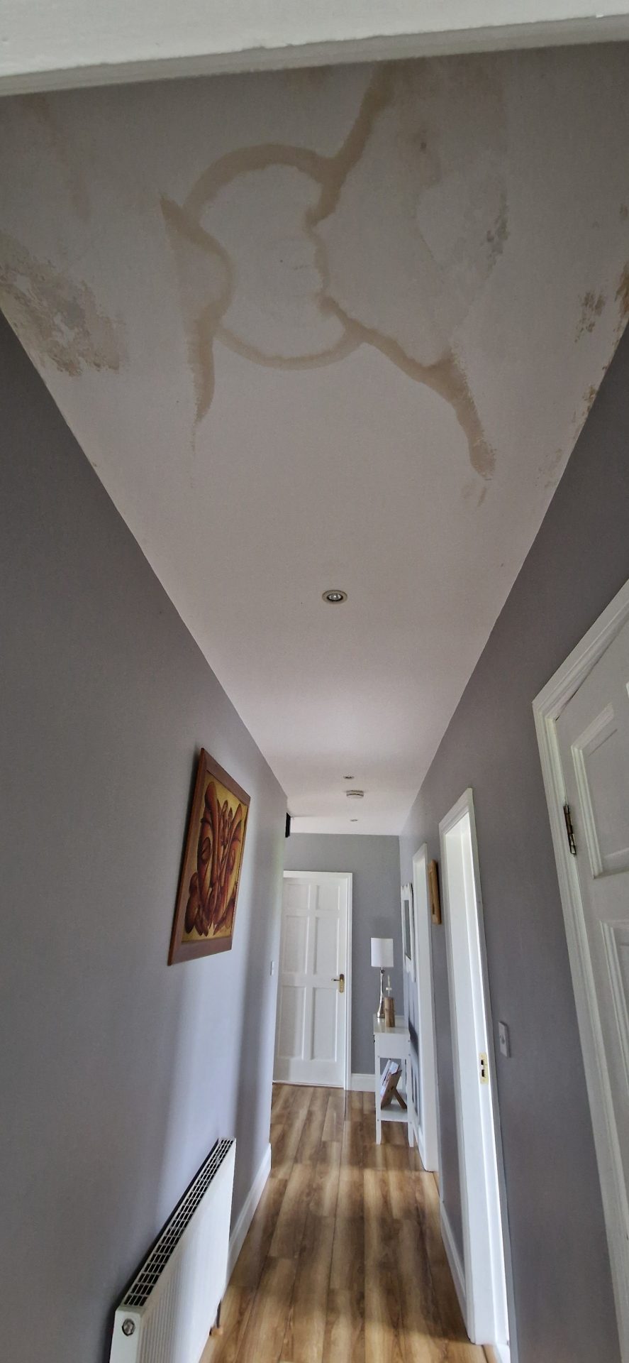 Water damage staining on a hallway ceiling from a burst pipe in an Irish home.